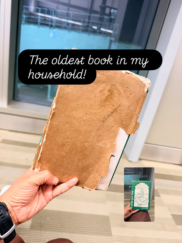 A worn Kathak textbook in a brown paper cover, held up in a hand